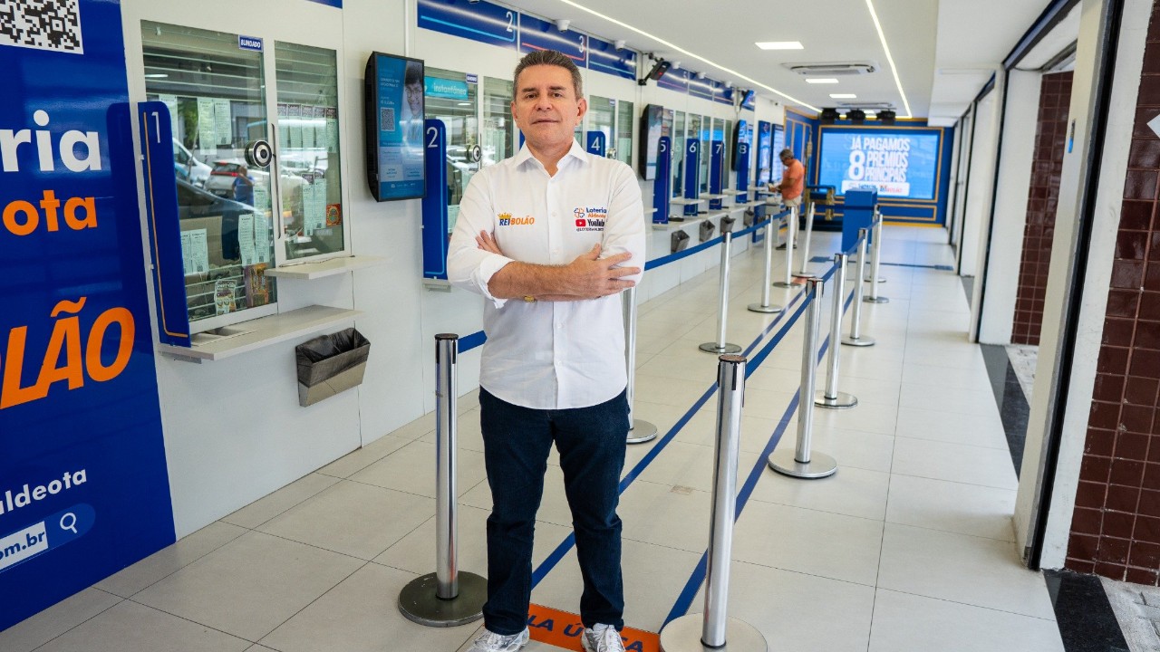 Alessandro Montenegro de camisa branca e braços cruzados em unidade da Loteria Aldeota