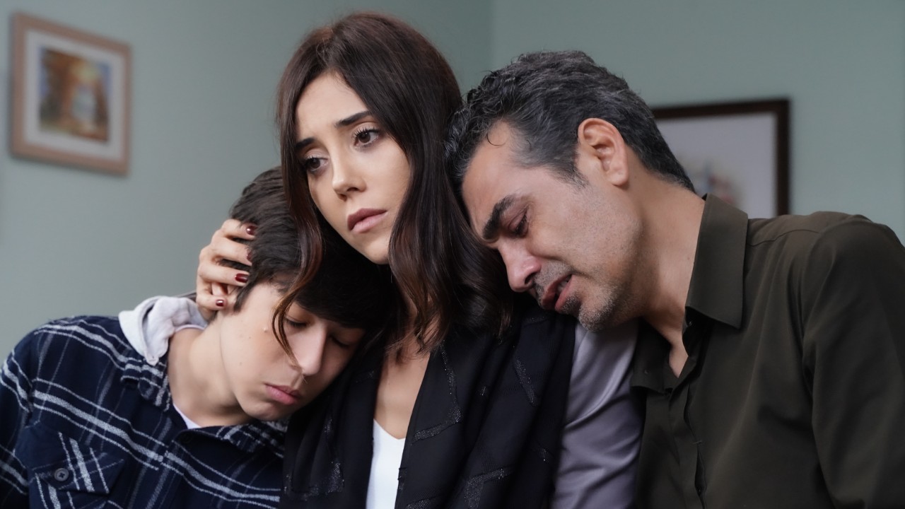 Ali (Alp Akar) e Volkan (Caner Cindoruk) apoiam a cabeça em Asya (Cansu Dere), que abraça o filho entristecida
