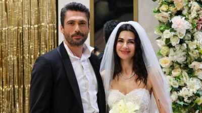 Hakan (Pamir Pekin) de terno ao lado de Ayça (Nesrin Cavadzade) vestida de noiva diante de flores em Coração de Mãe
