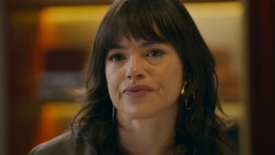 Ingrid (Agatha Moreira) com expressão séria e olhos marejados em ambiente interno na novela Quem Ama Cuida
