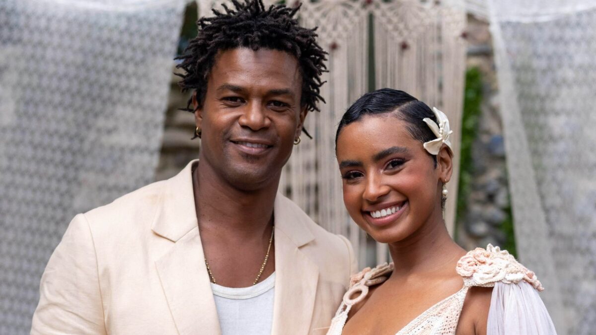Leandro (David Junior) e Eduarda (Gabz) sorriem lado a lado com roupas claras em cena da novela Coração Acelerado