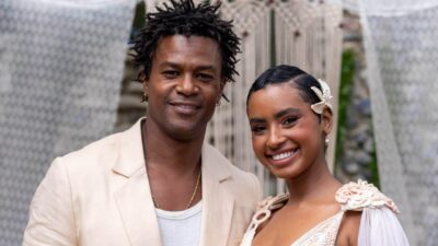 Leandro (David Junior) e Eduarda (Gabz) sorriem lado a lado com roupas claras em cena da novela Coração Acelerado