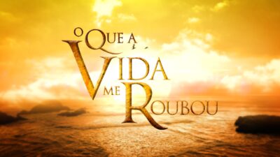Logotipo da novela O Que a Vida Me Roubou em letras douradas sobre céu alaranjado com nuvens iluminadas e mar ao pôr do sol ao fundo