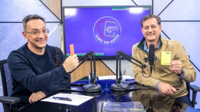 Maurício Noriega e Sálvio Spinola exibem cartões diante de microfones no estúdio do Giro do Apito