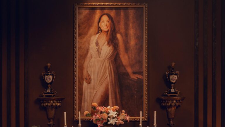 Retrato da Falecida (Susana Vieira) emoldurado sobre altar com flores e velas no reality Herança em Jogo
