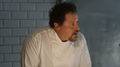Carl Casper (Jon Favreau) de uniforme branco de chef em cena do filme Chef