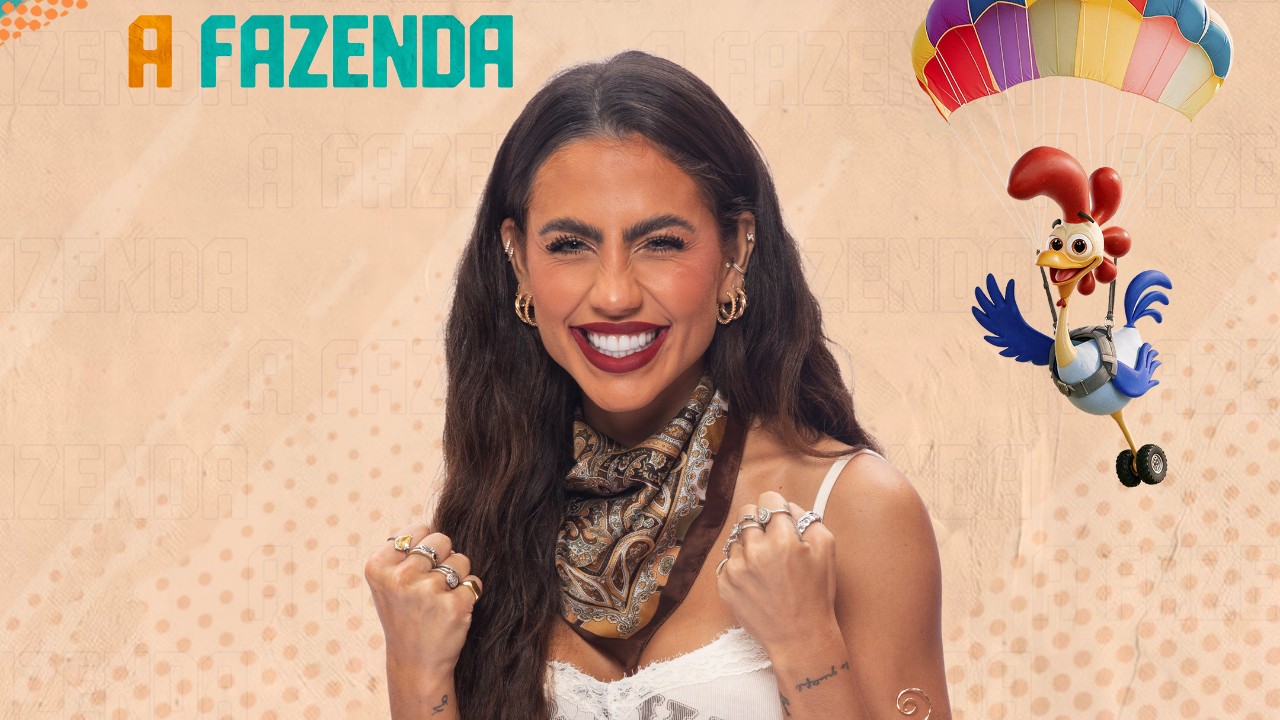 Caterine Bascoy sorri com lenço estampado no pescoço e punhos erguidos diante do logo de A Fazenda