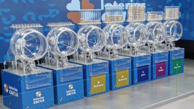Globos transparentes das Loterias Caixa alinhados para sorteios, com tubos de bolas numeradas na parte superior
