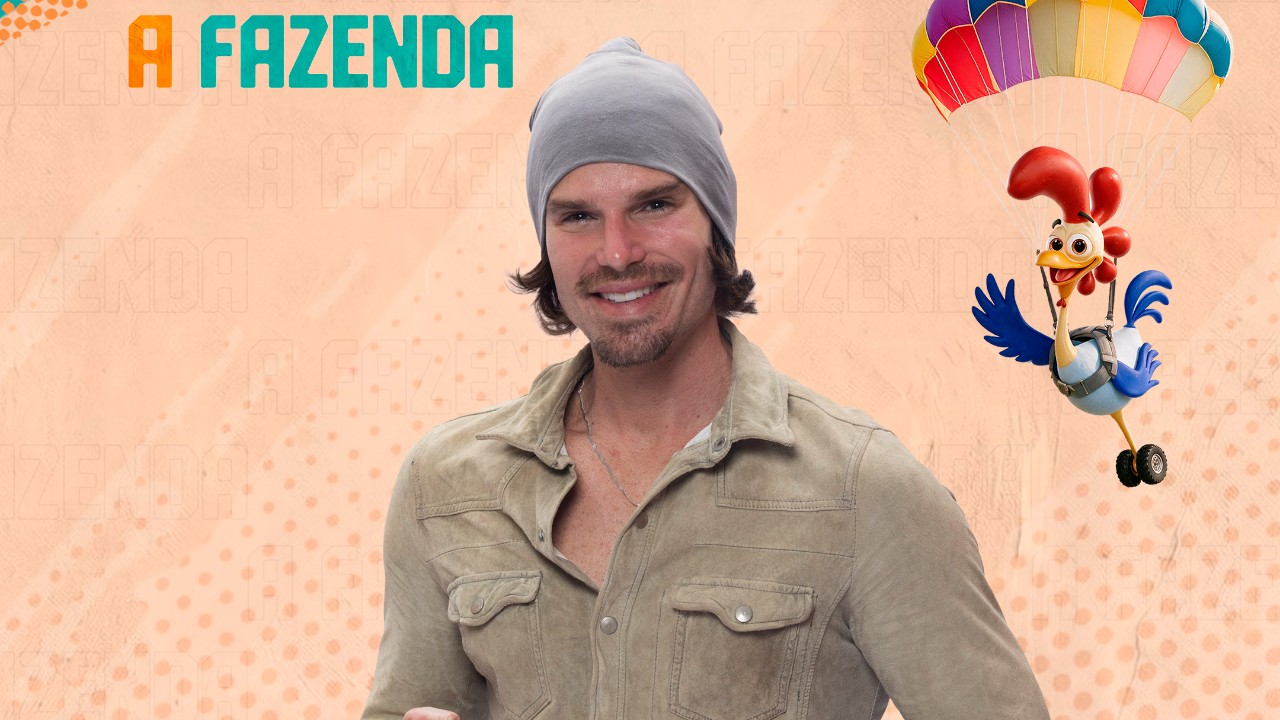 Jonatas Faro sorri de gorro cinza e camisa bege diante do logo de A Fazenda e galo de paraquedas