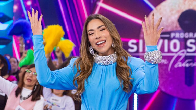 Patricia Abravanel sorri com os braços erguidos no palco do Programa Silvio Santos diante da plateia