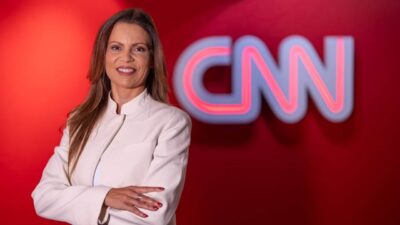 Patrícia Ellen posa de braços cruzados em frente ao logotipo da CNN Brasil