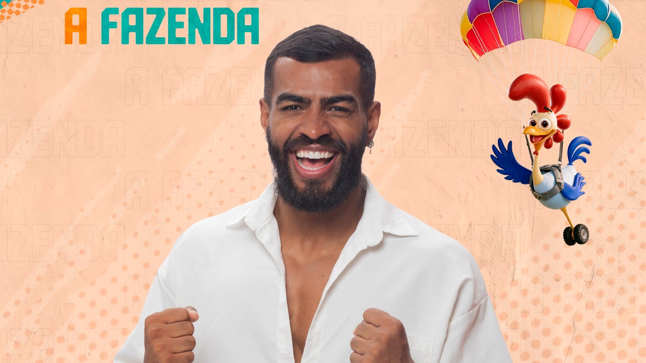 Rikardo Negro sorri de camisa branca com os punhos erguidos diante do logo de A Fazenda e galo de paraquedas