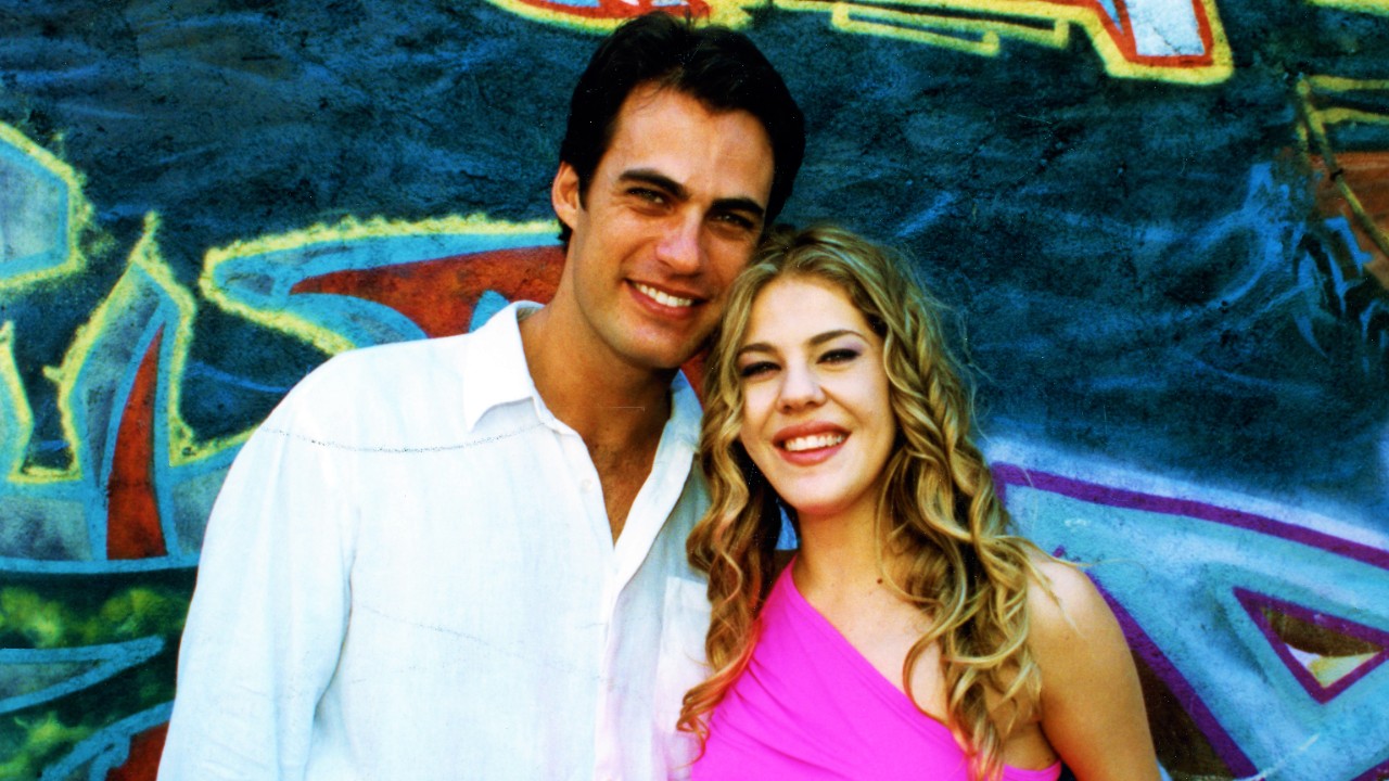 Rodrigo (Carlos Casagrande) e Marisol (Bárbara Paz) sorriem juntos diante de muro com grafites