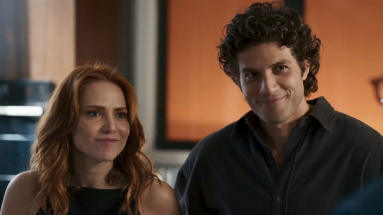 Adriana (Leticia Colin) e Pedro (Chay Suede) sorriem lado a lado, com roupas escuras, em Quem Ama Cuida