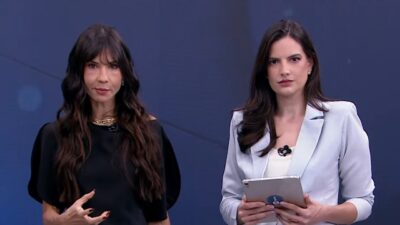 Amanda Klein de preto e Marina Demori de blazer azul-claro com tablet nas mãos em estúdio de televisão