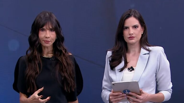 Amanda Klein de preto e Marina Demori de blazer azul-claro com tablet nas mãos em estúdio de televisão