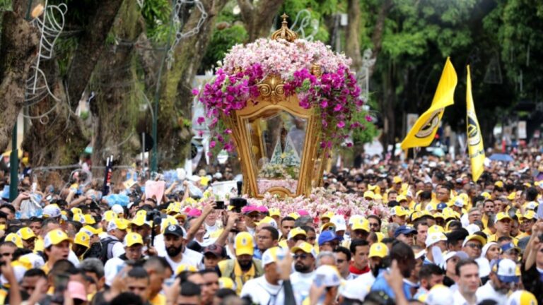 Multidão acompanha berlinda dourada enfeitada com flores brancas e rosas, com a imagem de Nossa Senhora de Nazaré ao centro