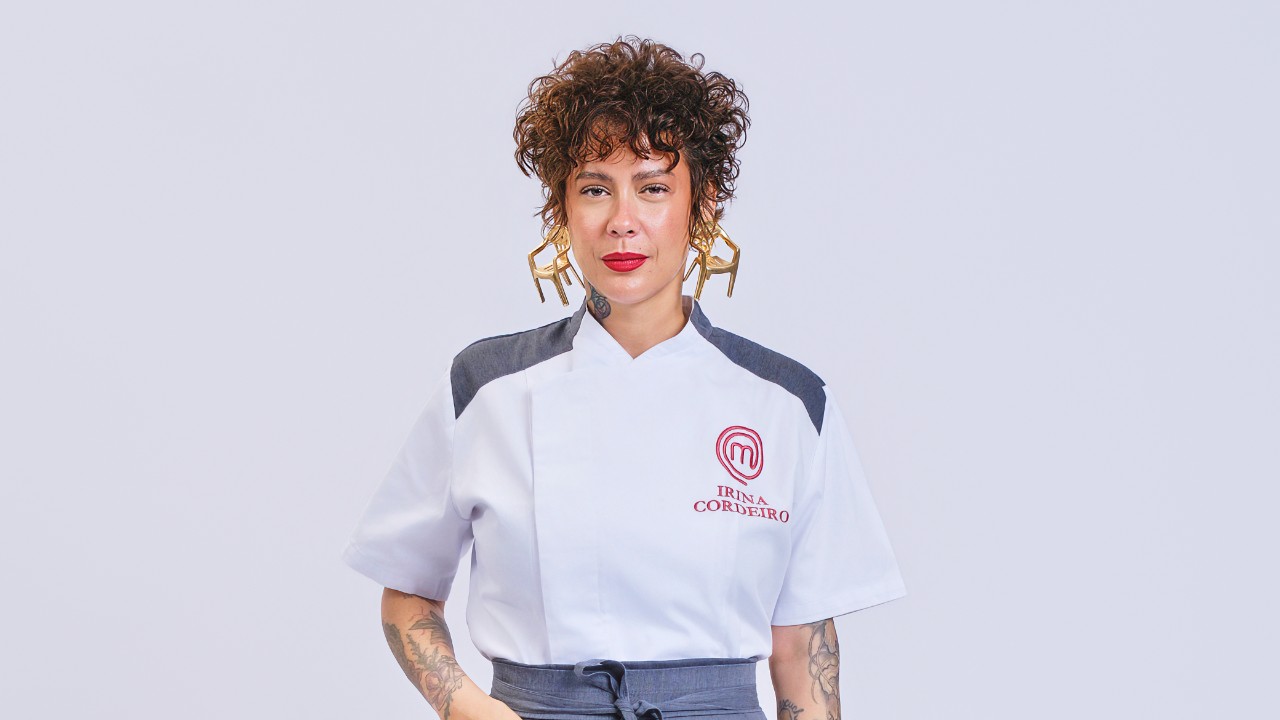 Irina Cordeiro posa com cabelo curto, brincos grandes e uniforme branco do MasterChef Profissionais
