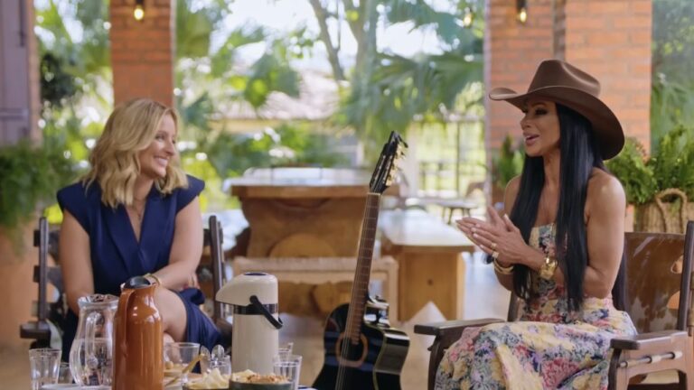 Ju Marques de azul sorri para Valéria Barros, de vestido floral e chapéu, durante conversa no Viver Sertanejo