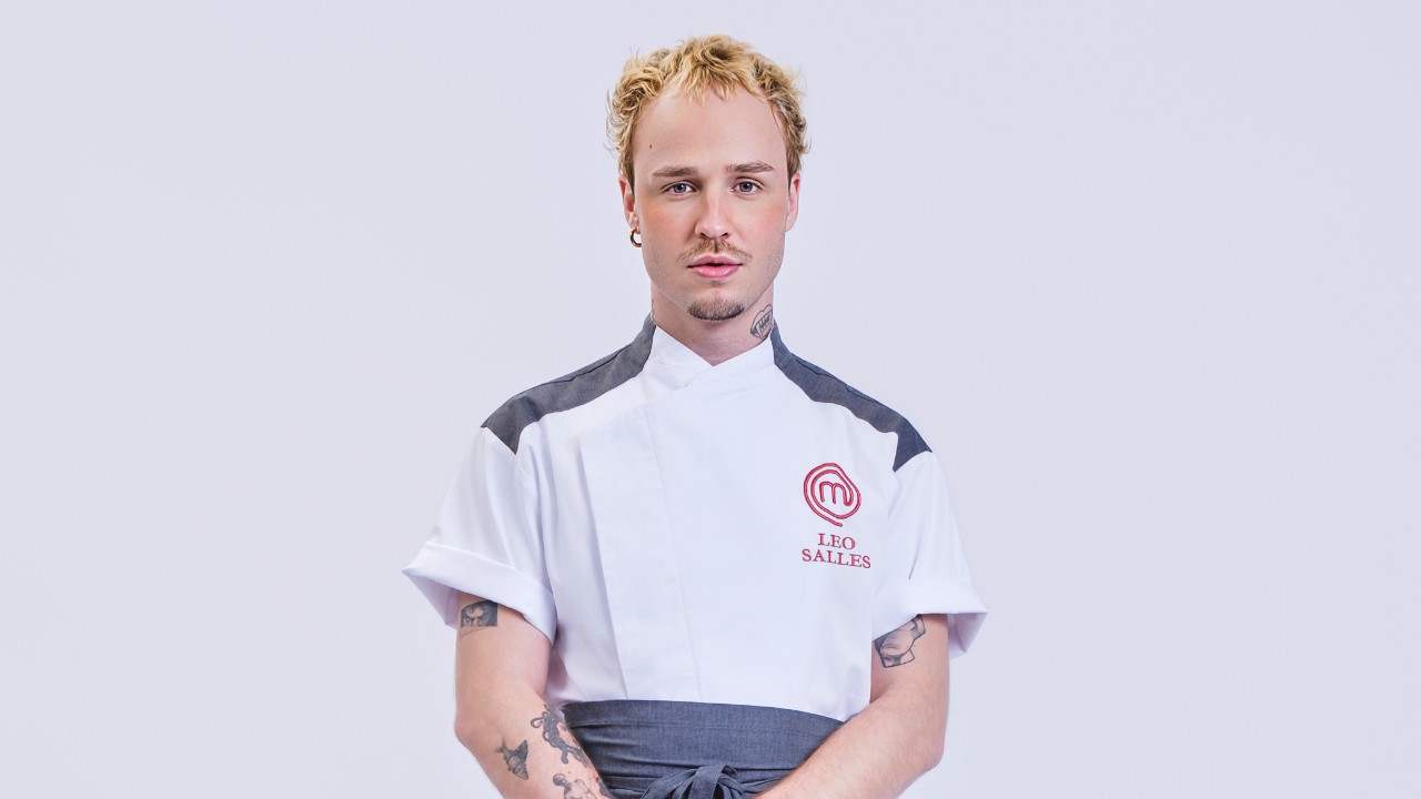 Léo Salles posa com cabelo loiro curto e uniforme branco do MasterChef Profissionais