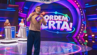 Marcos Mion apresenta o quadro Na Ordem Certa no palco do Caldeirão, com duas participantes em púlpitos e cenário iluminado por luzes coloridas