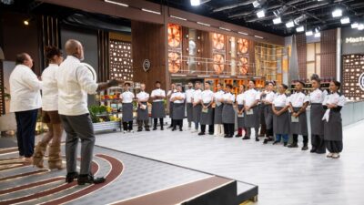 Participantes do MasterChef Profissionais em fila diante dos jurados no estúdio da competição