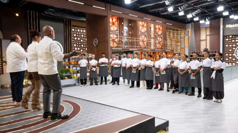 Participantes do MasterChef Profissionais em fila diante dos jurados no estúdio da competição