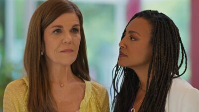 Nair (Luísa Thiré) de blusa amarela e Bela (Sheron Menezzes) de tranças olha para ela em cena de Por Você