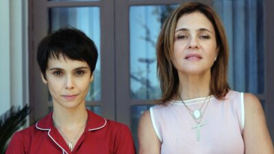 Nina (Débora Falabella) de camisa vermelha e Carminha (Adriana Esteves) de blusa rosa posam lado a lado