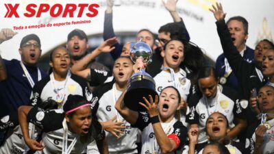 Jogadoras de futebol comemoram título com troféu erguido durante cerimônia de premiação, em imagem com a marca da Xsports