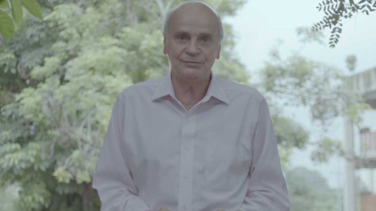 Drauzio Varella vestindo uma camiseta branca com árvores ao fundo
