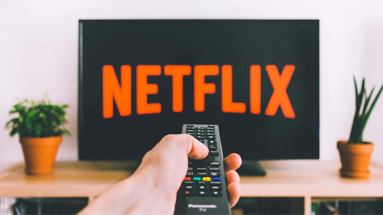 Controle apontado para TV com logo da Netflix na tela